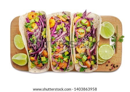 Delicious tacos with shrimps, avocado, onion and lime on a wooden board. Classic Tex-Mex cuisine meal. Top view shot, directly above studio shot on white background.