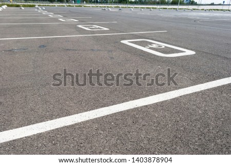 White disabled sign on a empty parking lot. Black tarmac texture with road marking 