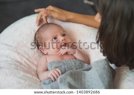 Happy mother giving cuddles and playing smiling with her cute newborn. Family, new life, childhood, beginning concept.