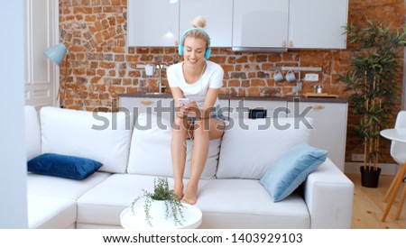 Woman with smartphone and headphones at home.