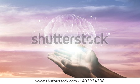 Male hands holding hologram of human brain with network connections on sunset sky background