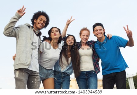 Summer holidays. Group of happy teens embracing and smiling at camera outdoor