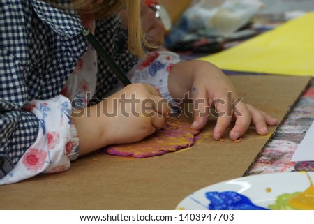 Little girl sitting at table and drawing form on the clay texture. Creative Art Workshop. 