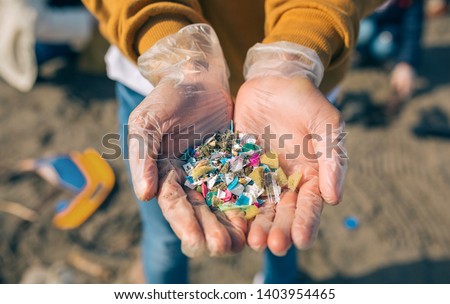 Detail of hands showing microplastics on the beach Royalty-Free Stock Photo #1403954465
