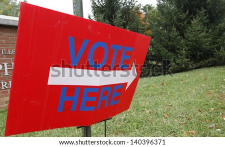 A vote here sign outside a voting station. Royalty-Free Stock Photo #140396371