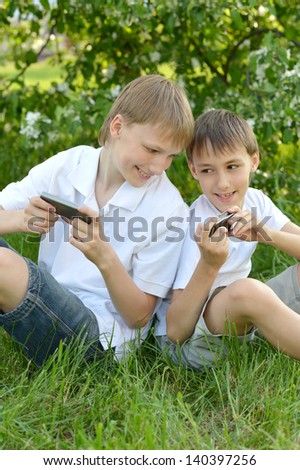 Two boys play a game on the phone outdoors