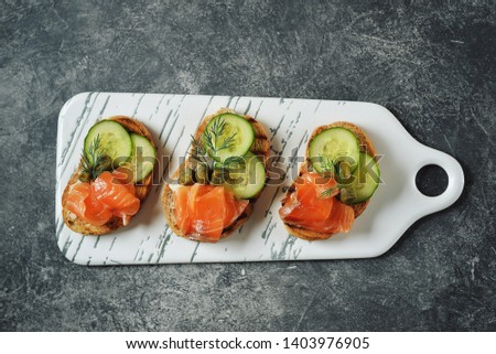 Mini sandwiches with butter, salted salmon, capers, cucumber and dill. Top view. Copy space. 