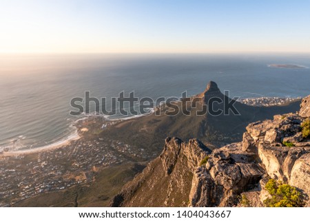 Landscape photo of Lion's Head at sunset with the ocean in the background and rocks in the foreground. Shot on Table Mountain, Cape Town, Western Cape, South Africa.