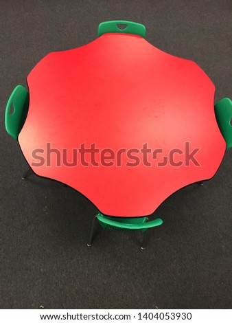 Oddly shaped red table with four green chairs
