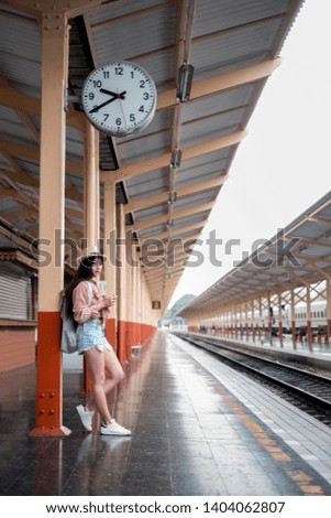 Smiling woman traveler with backpack holding vintage camera on holiday relaxation at the train station,relaxation concept, travel concept
