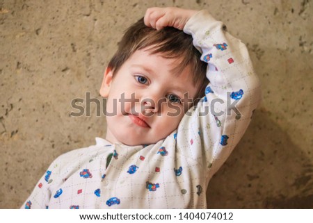 Portrait of a boy against the background of a concrete wall. The boy smiles. The boy is looking at the camera.