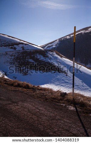 Road sign in the snow on the road to arrive in Castelluccio di Norcia, Umbria, Italy