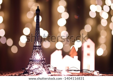 The Eiffel Tower model on a wooden table is decorated with lights on Christmas day.
