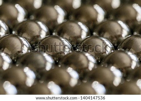 Close-up and perspective with the blurring of many objects forming an ordered structure. Metal shiny balls to shoot from a sling, evenly arranged.