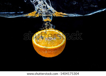 Orange with frozen water splash and drops on the black background - healthy summer freshly squeezed fruit juices.