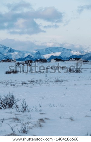 Isolated small village in a white winter landscape backed by mountains. 