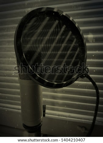 microphone and pop up filter concept grunge photo. blinds shadow falls on him