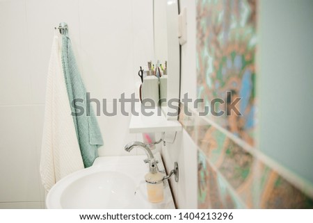 bathroom with white tiles, sink, mirror, white towels and turquoise hanging on the wall