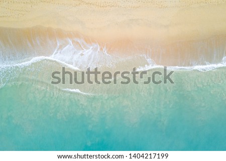 Aerial view of turquoise ocean wave reaching the coastline. Beautiful tropical beach from top view. Andaman sea in Thailand. Summer holiday vacation concept Royalty-Free Stock Photo #1404217199