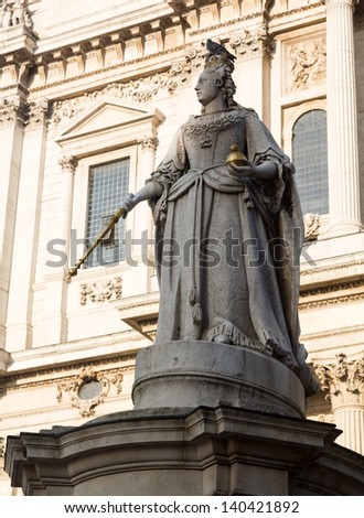 Statue of Queen Anne with bird perched on crown in St Pauls Cathedral in London England at dusk as the sun is setting low in sky.