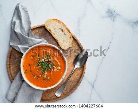 Gaspacho soup on round wooden tray over white marble tabletop. Bowl of traditional spanish cold soup puree gazpacho on light marble background. Copy space for text or design. Top view or flat lay. Royalty-Free Stock Photo #1404227684
