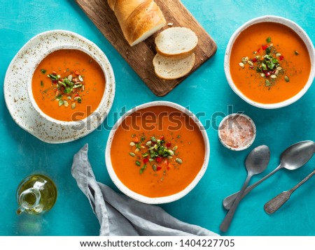 Gaspacho soup on blue tabletop. Three bowls of traditional spanish cold soup puree gaspacho or gazpacho on bright blue background. Top view or flat lay. Royalty-Free Stock Photo #1404227705