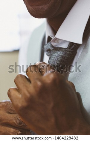 Black man fixing tie for wedding.