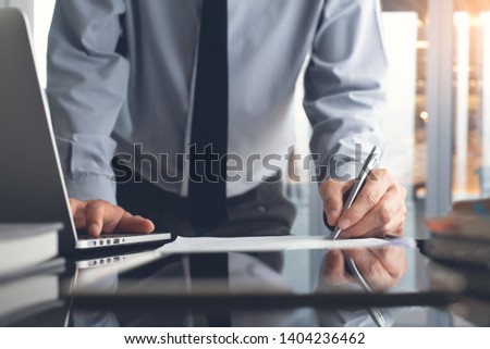 Signing contract, business deal concept. Businessman working in modern office, make a deal, signing official contract with laptop computer, digital tablet and business document on desk, close up