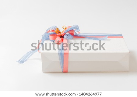 Gift box tied with blue and pink ribbons on white background