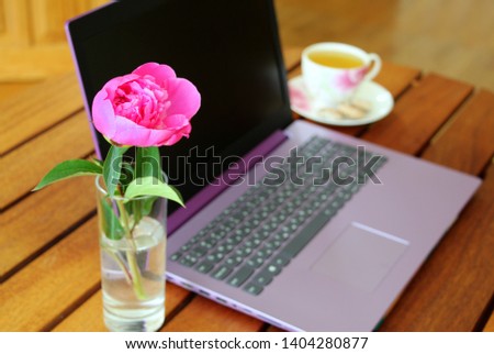 Beautiful female workplace. Remote work as a woman. Purple notebook, pink peony and herbal tea on a wooden table. Inspiration, energy, positive.