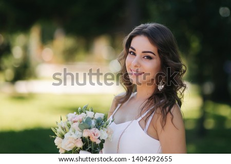 Portrait of yound girl with bouquet. Charming lady in sunny summer day. Stylish woman