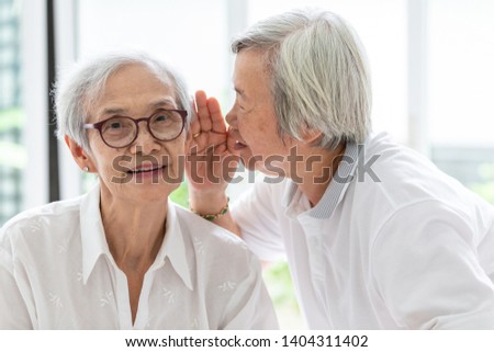 Asian senior woman holding hand near mouth telling funny,gossips on ears to friend,speaking in elderly woman ear and near face,having difficulty in hearing,hard to hear,hearing impaired old people Royalty-Free Stock Photo #1404311402