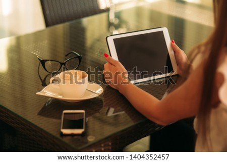 Mid selection of young girl use a tablet and drink cappuccino. The girl in the cafe is smiling