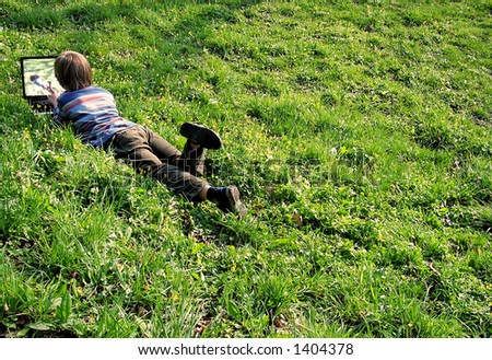 Child with notebook lays on a grass.