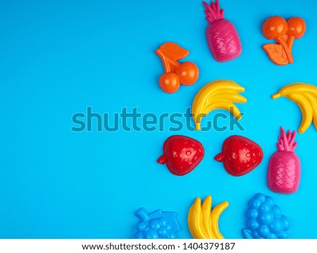 multicolored plastic toys fruits on a blue background, empty space