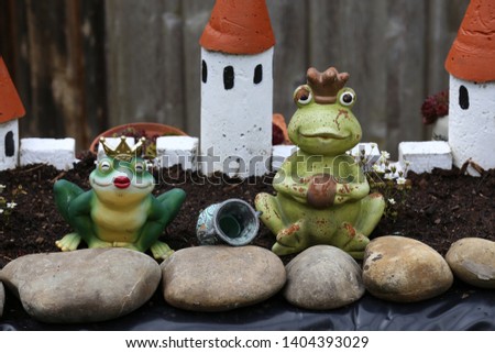 Decorative frogs stand near the garden pond