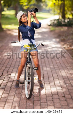 attractive young woman taking pictures on her bike outdoors
