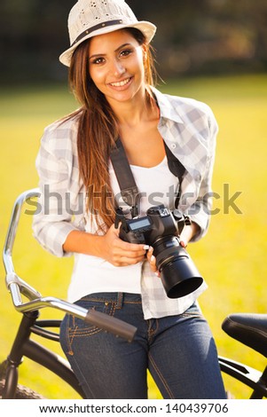 pretty woman with camera sitting on bicycle outdoors