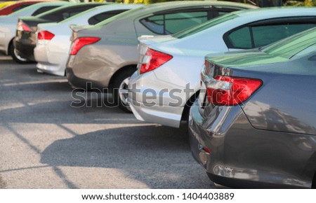 Closeup of rear, back side of brown car with  other cars parking in outdoor parking lot in bright sunny day. The mean of simply transportation in modern world.