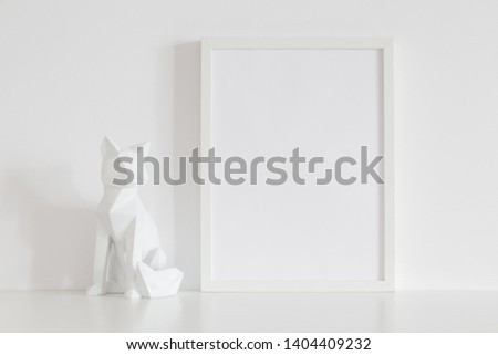 Photo frame mock up and origami fox design home decoration against white wall.