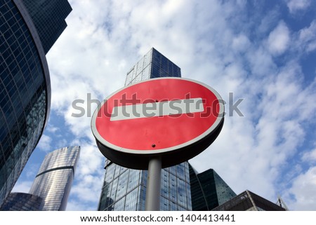Road Sign travel is prohibited against the background of cloudy sky and glass skyscrapers.