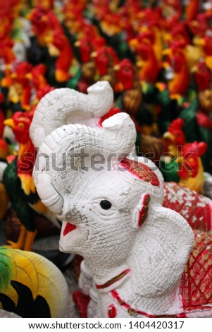 Statues of white elephants with trunks raised up at a Buddhist temple in southeast Asia.