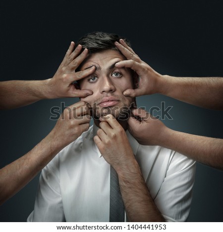 A male model surrounded by hands like his own thoughts on dark background. A young man doubts, can't choose the right decision and loses sleep. Concept of mental problems, troubles in work, indecision Royalty-Free Stock Photo #1404441953
