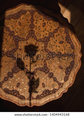 wooden indian table, shadow of rose, natural light, oriental ornaments,