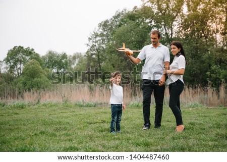 Father, mother and son playing with toy airplane in the park. friendly family. People having fun outdoors. Picture made on the background of the park and blue sky. concept of a happy family.