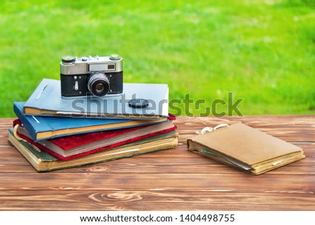 Old photo album with photos on a beautiful brown wooden table on the background of nature and old cameras.Copy space.