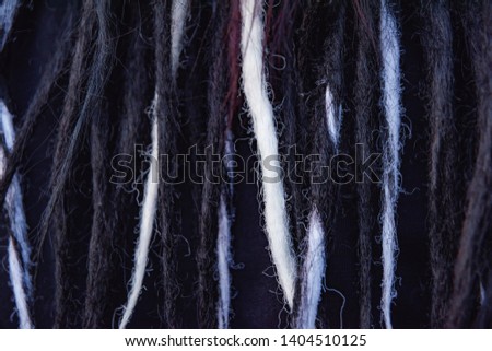 The texture of weaving dreadlocks on the head. Artificial hair texture. Black and white dreadlocks and burgundy hair close-up