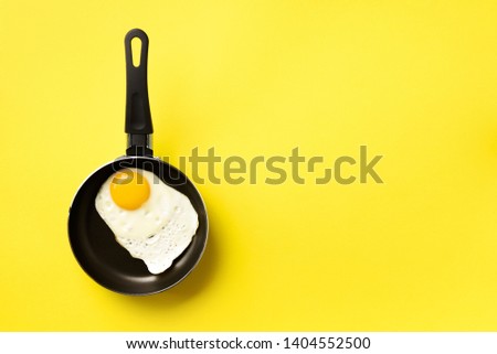 Creative food concept with fried egg on pan over yellow background. Top view. Creative pattern in minimal style. Flat lay
