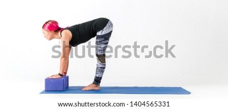 Sporty girl with pink hair trains on a blue fitness Mat bringing the body in order