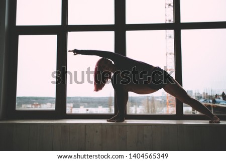 Girl doing gymnastics on the background of the window